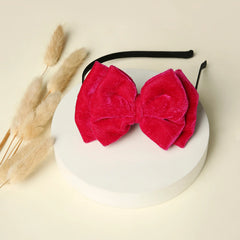 Velvet Bow Hairband - Pink Double Layered displayed on a white platform with dried flowers, showcasing its plush texture and elegant design.