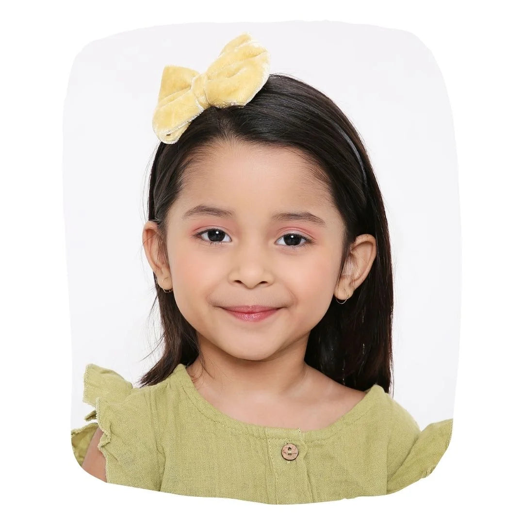 Beige velvet hairband with big bow worn by a smiling girl, ideal for kids' fashion and daily wear. Soft, stylish fit for ages 3-10.