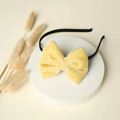 Beige velvet big bow hairband displayed on a round white platform with dried florals, perfect for girls' accessories and gifting.