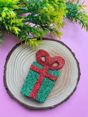 Festive Christmas Glitter Hair Clip styled on a wooden display with greenery, showcasing its sparkle and holiday charm for kids.