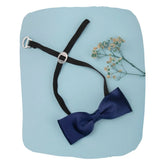 Blue adjustable satin bow tie for boys with black clip-on strap, displayed on a pastel background with floral accent. Ideal for ages 1-5.