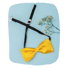 Adjustable satin bow tie for boys in yellow with black clip-on strap, styled flat on a blue background with floral accent.