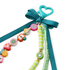 Detail view of Fimo Bead Bag Charm - Green Ribbon Bow; includes heart-shaped clip, colorful beads, and durable ribbon for easy attachment.