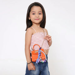 Young girl carrying an orange handbag adorned with the Blue Fimo Bead & Star Bag Charm, ideal for kids' fashion accessories.