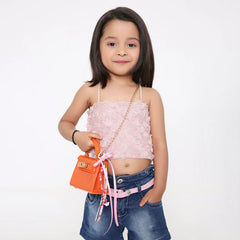 Young girl holding an orange handbag adorned with a pink beaded bag charm featuring hearts, bows, and smiley beads. Ideal for kids' fashion accessories.