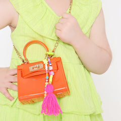 Close-up of orange handbag with Neon Yellow Beaded Bag Charm featuring custom name beads and pink tassel. Perfect for kids' fashion bags.