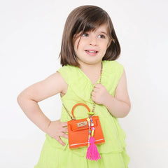 Girl in lime green dress holding orange handbag with Neon Yellow Personalized Beaded Bag Charm. Fun and stylish accessory for young girls.