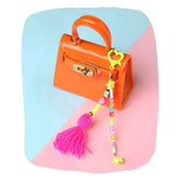Neon Yellow Beaded Bag Charm personalized with colorful beads and pink tassel clipped to an orange mini handbag. Trendy accessory for kids' bags.