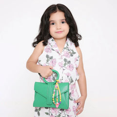Young girl holding a green purse adorned with a personalized orange bag charm featuring fun beads and custom name letters for kids.