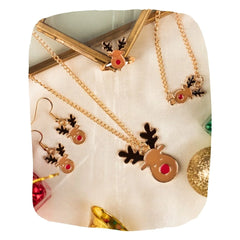 Christmas Jewelry Set - Rudolf Reindeer Design by Arendelle displayed on festive fabric with pendant, earrings, ring, and bracelet for girls.