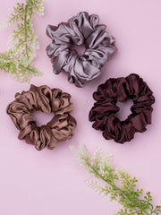 Silk Satin Hair Scrunchies in brown, bronze, and dark chocolate shades, styled on a pink background with decorative leaves.