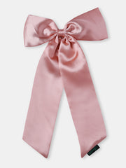 Close-up of large pastel pink satin silk hair bow with long tails. Smooth finish ideal for formal and casual hairstyles.