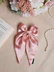 Handmade Satin Silk Hair Bow in pastel pink displayed on fabric with floral and pearl accents, ideal for elegant hairstyles.