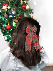 Girl wearing red plaid bow hair accessory from the festive Christmas glitter set, styled for a holiday look near a decorated Christmas tree.