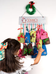 Girl interacting with Personalized Advent Calendar for Girls, featuring 12 hanging pouches filled with holiday-themed hair accessories.