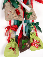 Close-up of 6-Day Dreamcatcher Christmas Advent pouches numbered 1 to 6 with holiday-themed decorations. Creative countdown gift for Christmas.