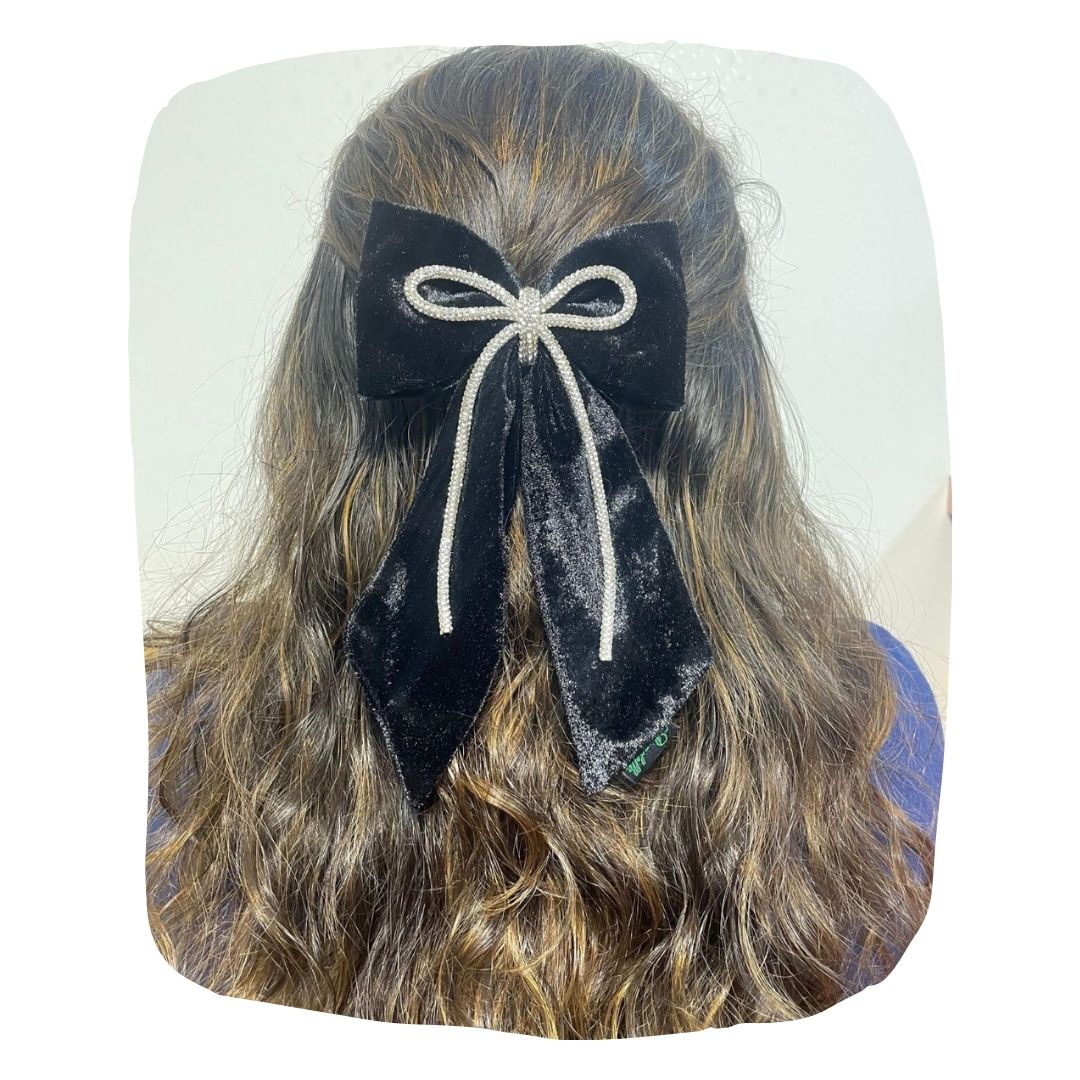 Girls black velvet hair bow with rhinestone cord, handmade and secured with a clip, styled on long wavy hair. Elegant accessory for kids.