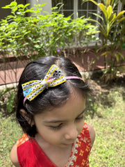 Girl wearing Navratri Hairband with colorful bow outdoors, ideal for Garba nights. Handcrafted accessory adds charm to traditional outfits.
