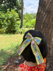 Pari Hoon Main Pigtail Bow styled on a girl's hair, perfect Navratri hair accessory for kids with colorful mirror work and lace detailing.