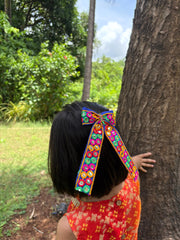 Back view of girl in festive dress wearing Dholida Pigtail Bow, a handcrafted Navratri hair accessory with ethnic detailing.