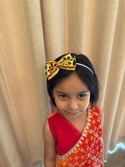 Girl wearing Kesariyo Hairband featuring vibrant mirror work and beads, ideal Navratri accessory for Garba and Dandiya celebrations.
