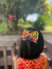 Colorful Kesariyo Big Tassel Bow for kids, worn during Navratri festivities, featuring traditional mirror work and multicolor tassels.