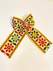 Close-up of Kesariyo Pigtail Bow featuring multicolor floral embroidery, ideal Navratri hair pin for girls' traditional attire.