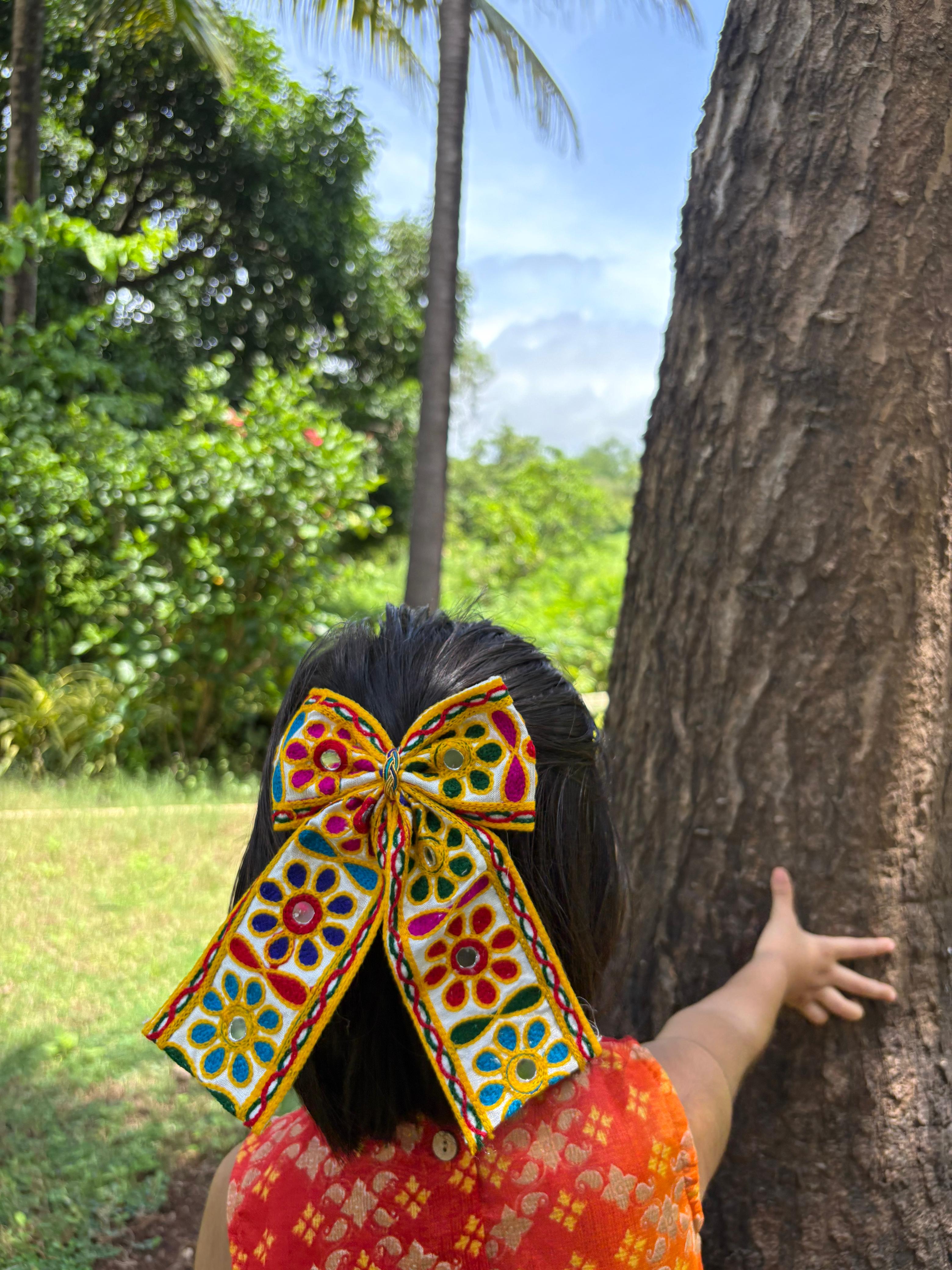 Girl wearing Kesariyo Pigtail Bow, a vibrant Navratri hair accessory with colorful embroidery, perfect for festive Garba outfits.