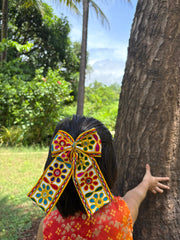 Girl wearing Kesariyo Pigtail Bow, a vibrant Navratri hair accessory with colorful embroidery, perfect for festive Garba outfits.