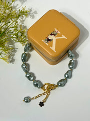 Close-up of grey baroque pearl Lumba Rakhi with gold chain and black flower charm, perfect as bracelet, necklace, or phone wristlet, SKU: RLB046