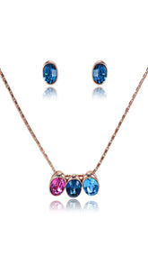 Swarovski Set Jewelry featuring a rose gold chain with colorful pink and blue crystal pendant and matching blue stud earrings. Elegant and dazzling style.