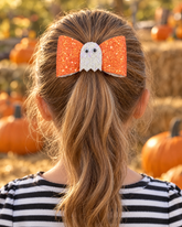 Little Boo orange glitter ghost hair bow on a girl's ponytail