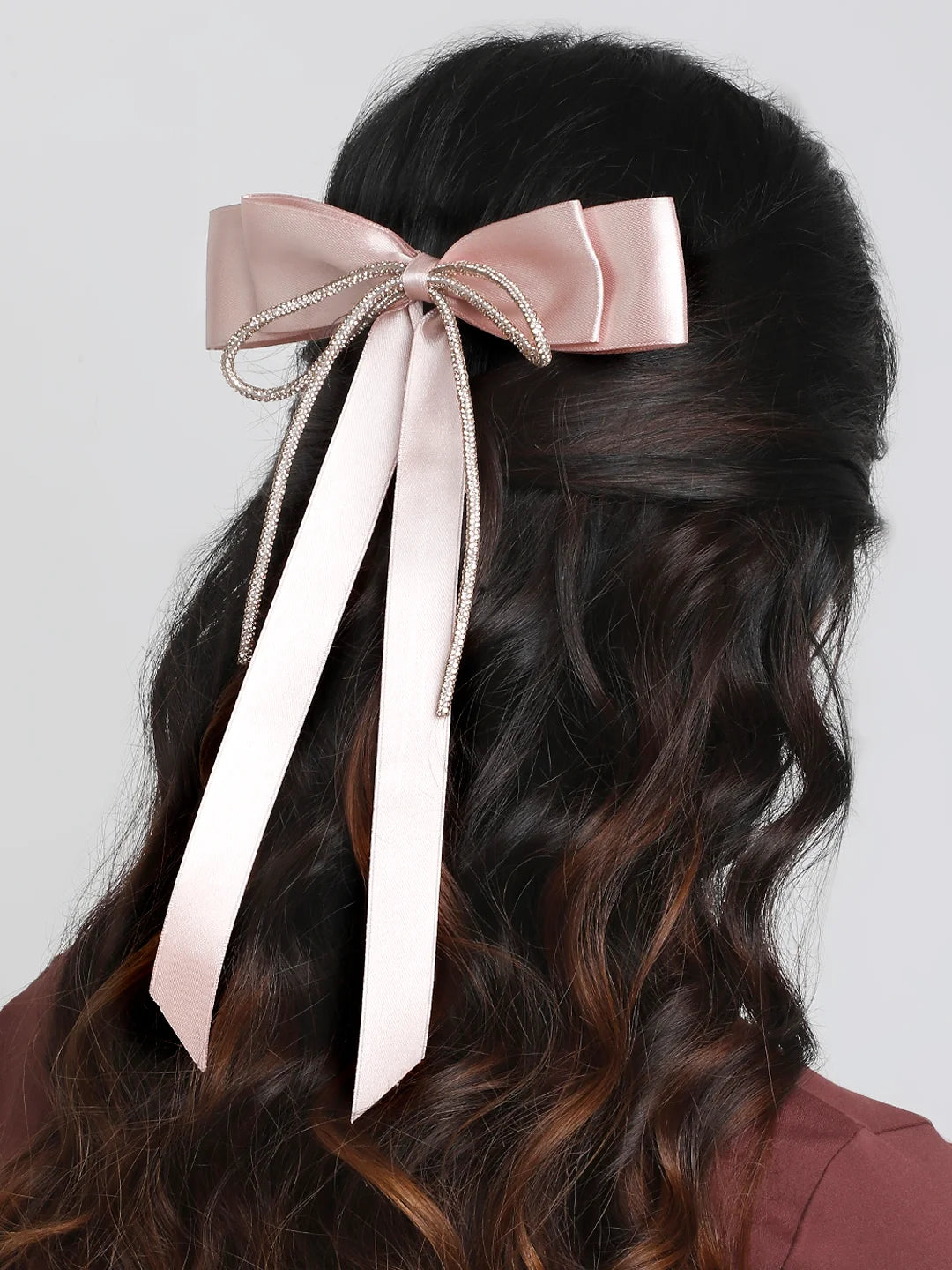 Pink satin hair bow with rhinestone loop worn on curled hair. Feminine and secure accessory for kids and women.
