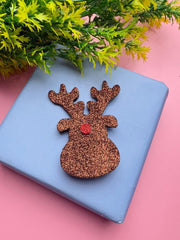 Festive Rudolph Reindeer Hair Pin displayed on blue gift box with greenery, great for holiday presentation.