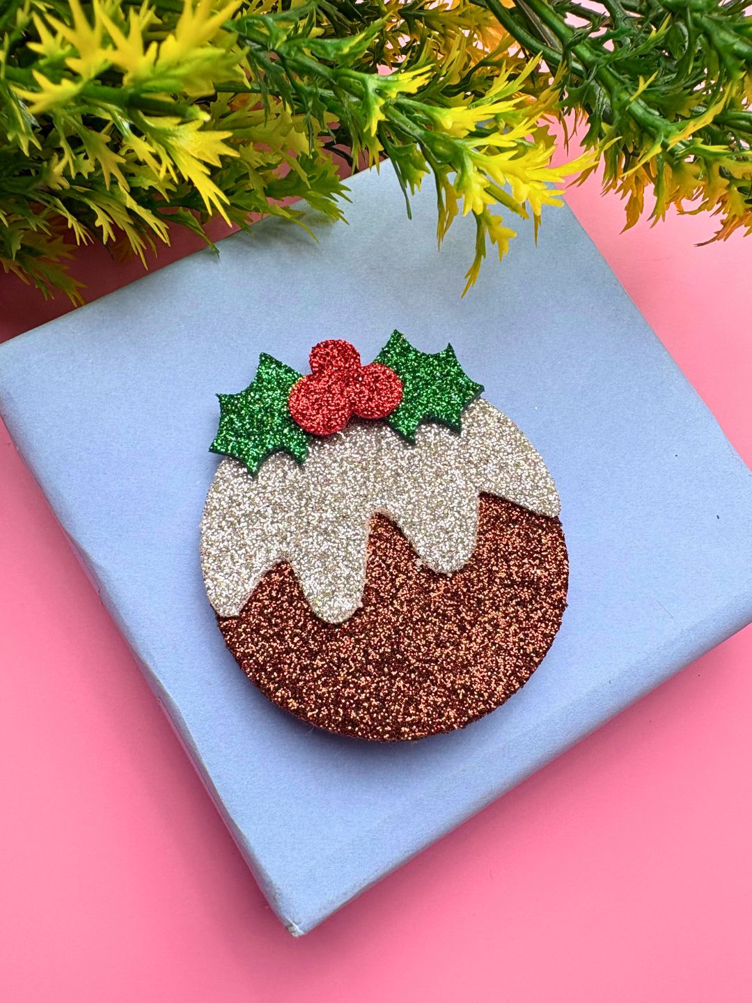 Sparkly Christmas Glitter Hair Clip styled on a gift box, featuring festive holly leaves and pudding design for holiday accessories.