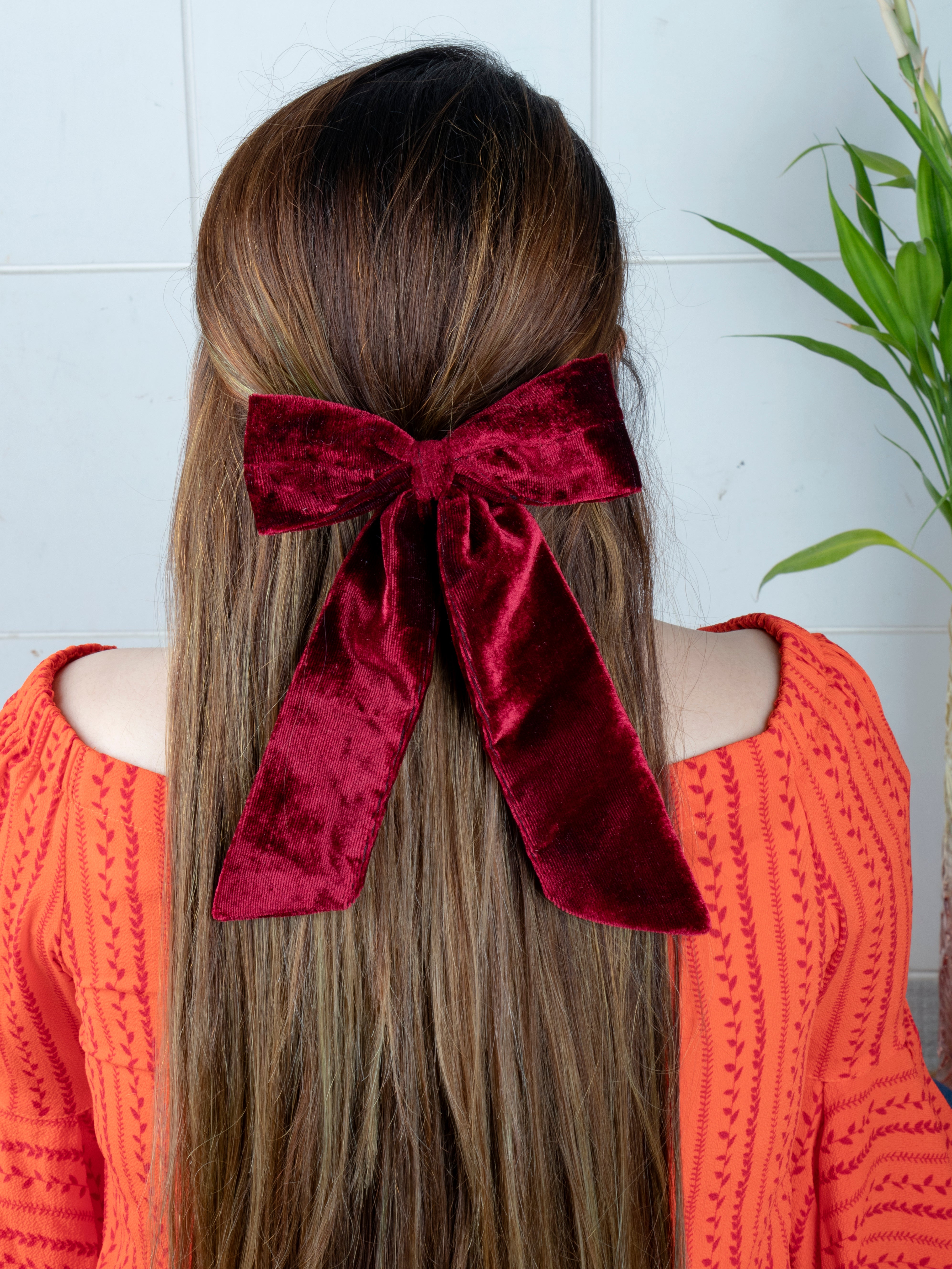 Girl with long hair wearing a deep red velvet bow from the Christmas glitter hair accessories collection, perfect for festive outfits.