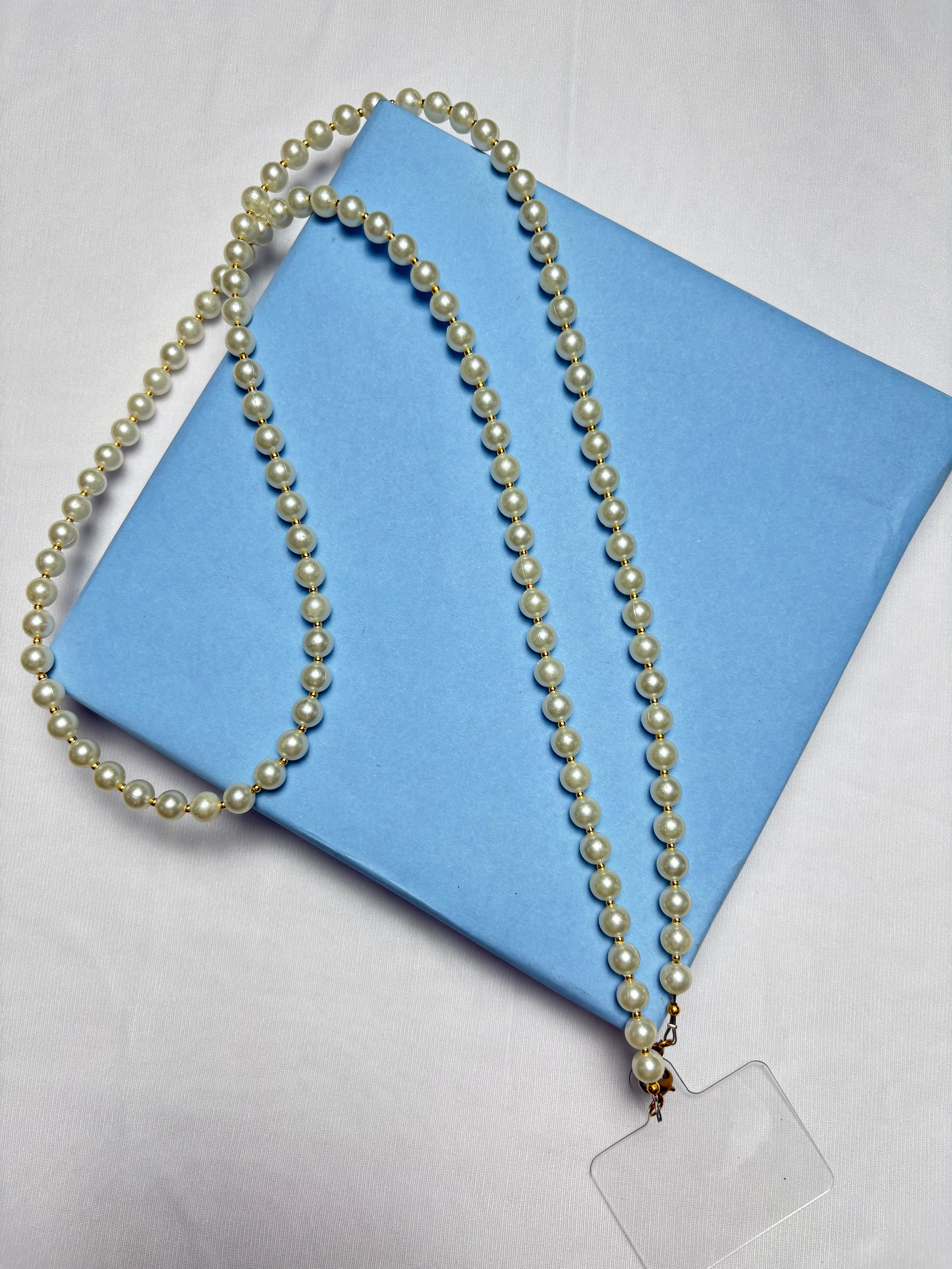 Navratri Pearl Phone Sling with white pearls displayed on a blue gift box, perfect for festive traditional outfits.