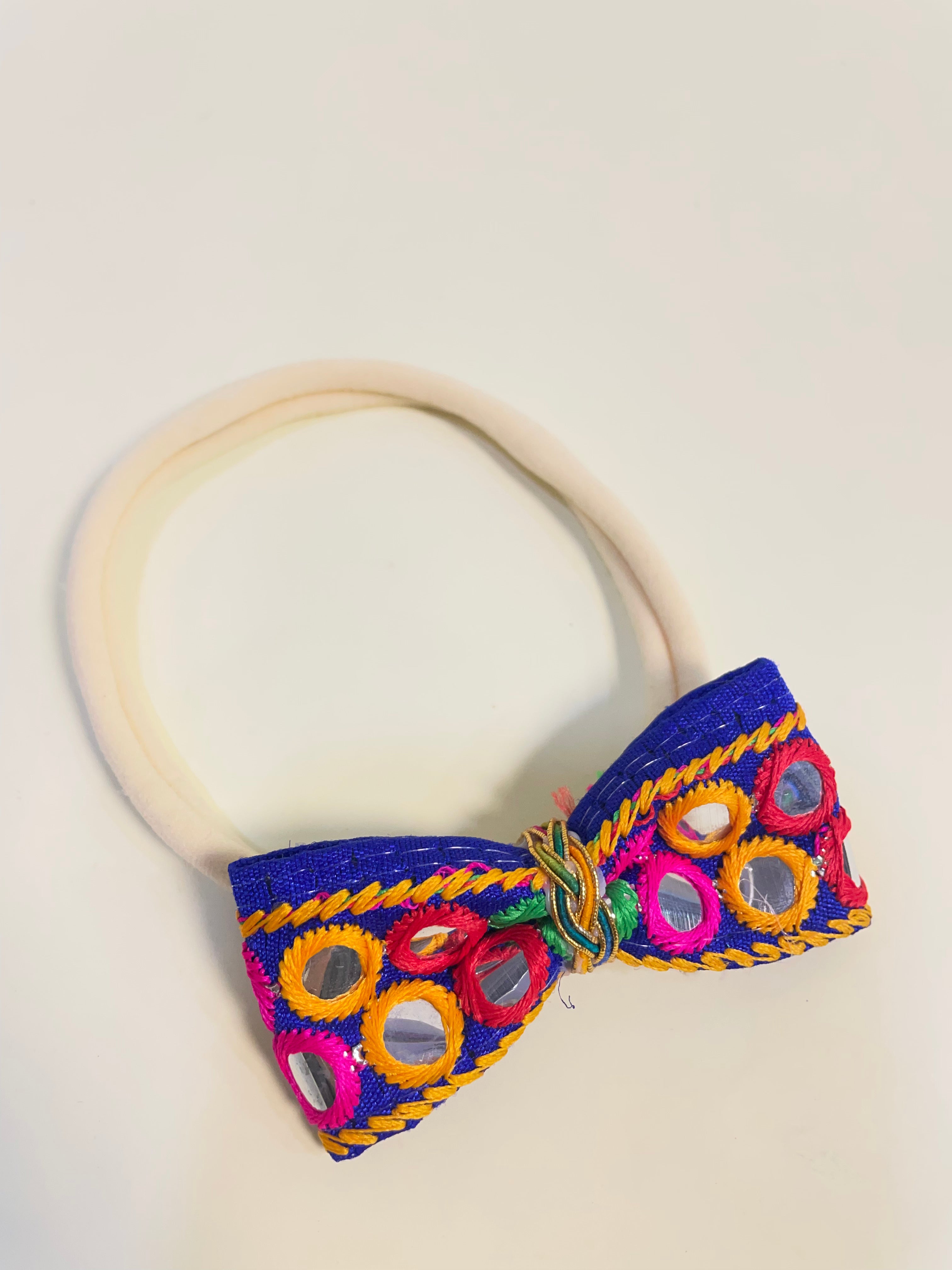 Dholida Baby Headband for Navratri featuring vibrant mirror work and multicolor embroidery on a soft elastic band. Ideal festive hair accessory for infants.