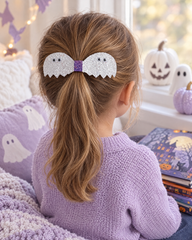 Girl reading Halloween books wearing the Ghostie Pair hair clip